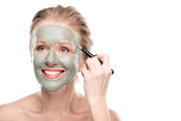 smiling mature woman Applying clay mask with cosmetic brush Isolated On White