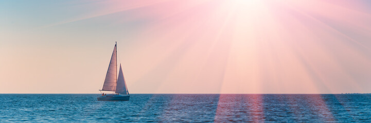 Banner 3:1. Sailboat in the sea in the evening sunlight over sky background. Luxury summer...
