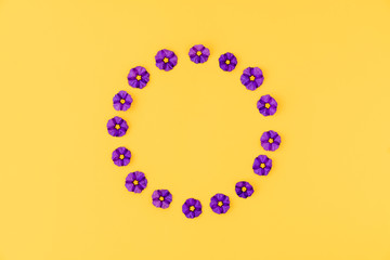 Flowers composition. Wreath made of  blue flowers on yellow background. Flat lay, top view