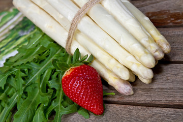 Weißer Spargel mit Rucola und Erdbeere auf einem Holztisch