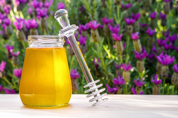 Jar of organic floral honey with a drizzle against lavender background . Outdoor.	