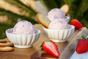 Tasty  strawberry ice cream  in bowl on table against nature flowers background	