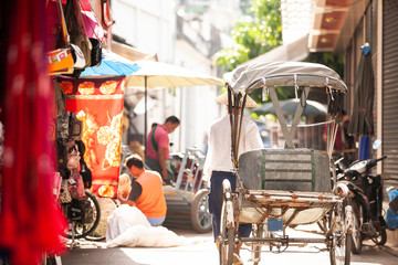 Cycle rickshaw and laborer on the township alley in Eastern Myanmar.
