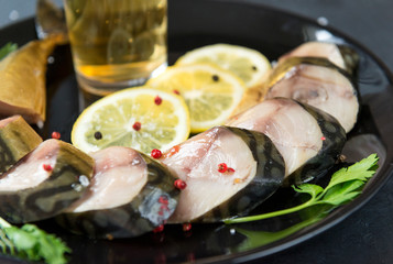 cold smoked mackerel with spices on a plate, lemon pieces, salted fish, beer snack
