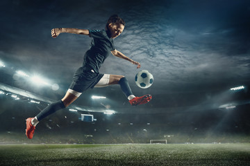 Fototapeta na wymiar Young female soccer or football player with long hair in sportwear and boots kicking ball for the goal in jump at the stadium. Concept of healthy lifestyle, professional sport, hobby, motion, movement