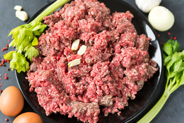 raw ground beef in a plate, celery, garlic cloves, eggs onion, meat