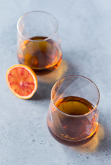 2 glasses of cognac on a gray background, a piece of orange
