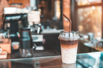 Two tone Iced coffee in coffee shop. Brown and white Ice coffee or caffe latte with milk in takeaway cup. copy space for text. Drink and food background.