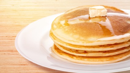 Stack of tasty pancakes with butter on a white plate