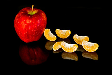 Apple and mandarin slices on a black background