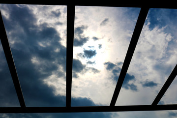 View of the cloudy sky through the iron bars. Iron lattice and sky