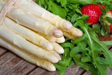 Weißer Spargel mit Rucola und Erdbeere auf einem Holztisch