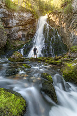 Man standing in front of waterfall in a forest