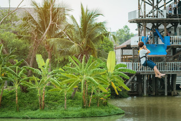 A male tourist flying on a zipline aka flying fox across the lake at Pattaya Floating Market, Thailand.