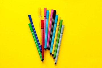  Multi-colored felt-tip pens on yellow background. Top view,business, office supplies. School office supplies. Minimal style. Colorful marker pen set. Vivid highlighter. Art, workshop, craft concept.