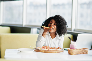 Сheerful business african american lady with afro hair, wear white blouse sitting at table, work...