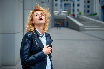 curly blonde young woman enjoying the walk in the city and feels happy in the modern cityscape