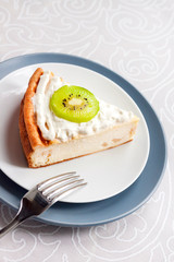 Homemade cottage cheese cake with kiwi fruit and cream on a plate
