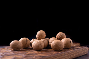 Bunch of walnuts on carved wooden board, dark background. Healthy nuts and seeds composition, background.