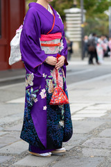 Fototapeta premium Young girl wearing Japanese kimono standing in front of Sensoji Temple in Tokyo, Japan. Kimono is a Japanese traditional garment. The word 
