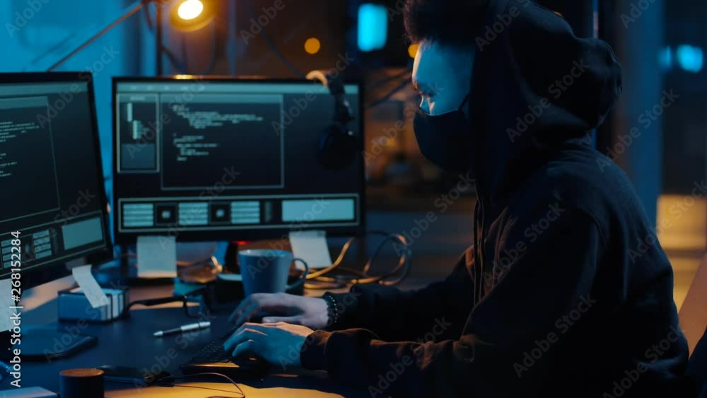 Poster cybercrime, hacking and technology concept - asian male hacker in mask writing code or using compute