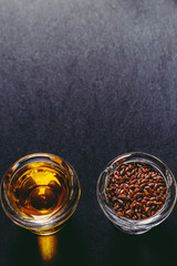 flax seeds and linseed oil in glass sauceboats on a black stone, space for text