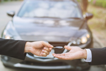 Car key, businessman handing over gives the car key to the other woman on car background. © methaphum