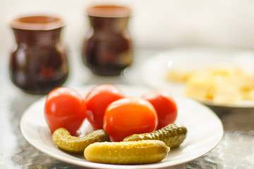 pickled cucumbers and tomatoes in a white plate on a sunny table