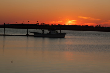 Sunset with a fishing boat moored to a dock