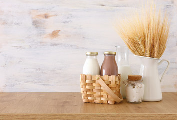 photo of milk and chocolate next to wheat over wooden table and white background. Symbols of jewish...