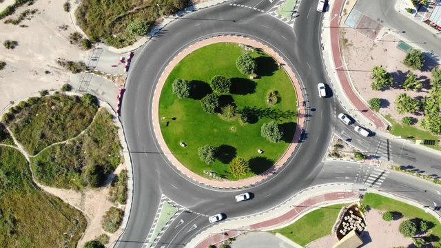 A roundabout on the spanish national road N332 taken vertically from above from the air with many vehicles in sunshine.