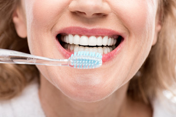 Cropped view of middle aged woman brushing Teeth Isolated On White