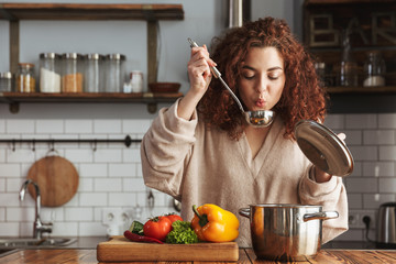 Photo of pretty caucasian woman holding cooking ladle spoon while eating soup at home
