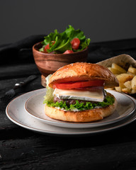 homemade burger with brie cheese on a dark backdrop