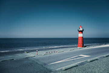 A red and white lighthouse at sea under a clear blue sky near Westkapelle in Zeeland, The Netherlands.