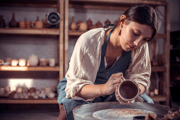 Stylish ceramist master  molding a vase of clay on a potter's wheel. Pottery workshop.