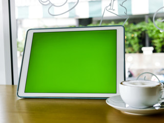 Green screen tablet and coffee mug on table, mock up.