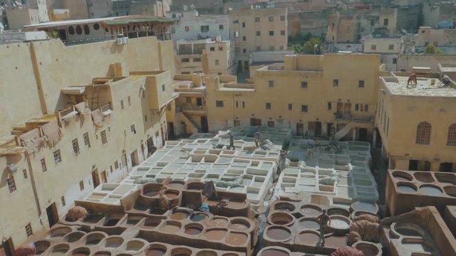 Overlooking the famous Tannery in Fez, Morocco with stone vessels filled with a colorful dyes as a historical tradition to dye materials panning through a metal fence