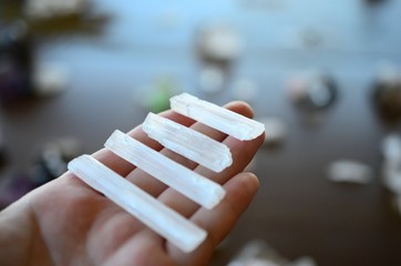 Woman's hand holding miniature selenite rods. Bright white healing selenite. Macro photo of healing...