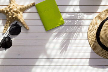 Summer travel accessories flat lay on white wood background. Passport, hat, sunglasses and starfish for woman's summer holidays. Beach fashion concept, top view.