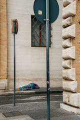 A homeless man sleeps under a colored blanket on the main street of the Vatican | ROME, ITALY - 12 SEPTEMBER 2018.