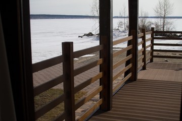 Veranda of dark brown timber. Beautiful sea view covered with ice and snow. Country rest.