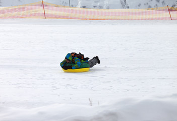 Fototapeta na wymiar Snow tubing on ski resort at sunny day in snowy mountains
