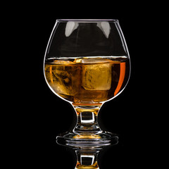 A round glass of whiskey brandy with ice, a wave and a small splash