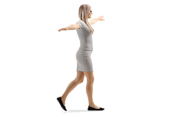 Young blond woman walking with arms spread