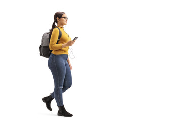 Fototapeta premium Female student walking and listening to music from a mobile phone