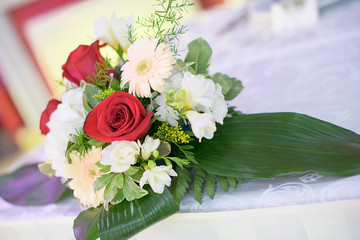 Romantic wedding decor for bride and groom or guests dinner tables at the reception venue or restaurant with beautiful floral centerpieces featuring red roses, pastel Gerbera daisies and greenery