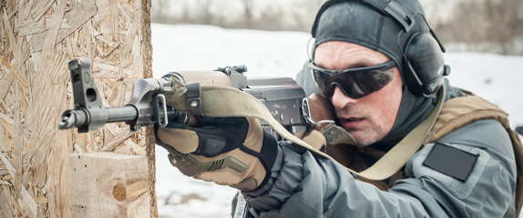 Special forces soldier in action, shooting from rifle machine gun