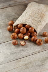 Obraz premium Macadamia nut on a wooden table in a bag, closeup, top view
