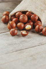 Macadamia nut on a wooden table in a bag, closeup, top view